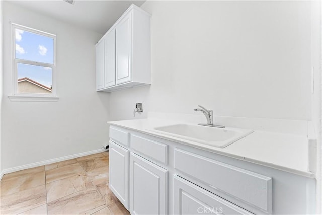 washroom with baseboards, a sink, and cabinet space