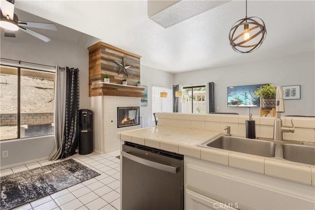 41787 Humber Dr, Temecula, CA 92591 - kitchen with stainless steel dishwasher, a sink, tile countertops, a tiled fireplace, and white cabinetry