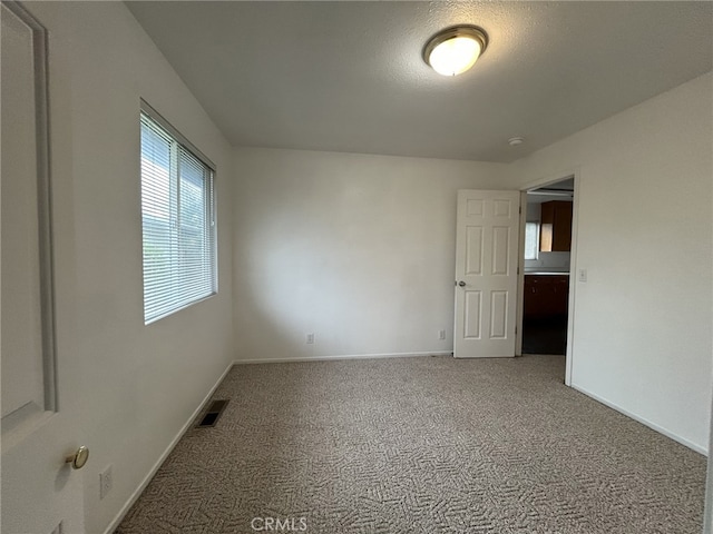 carpeted spare room featuring baseboards and visible vents