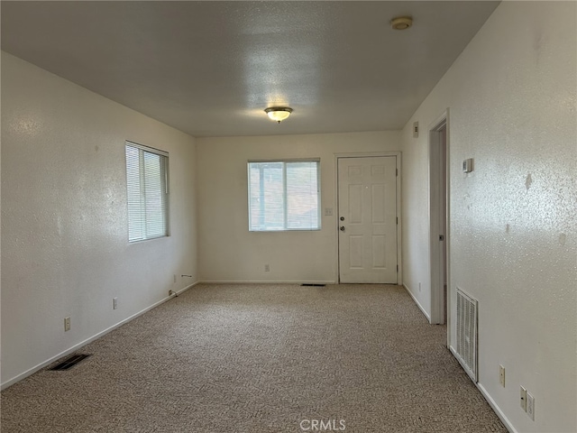 empty room with baseboards, carpet flooring, and visible vents
