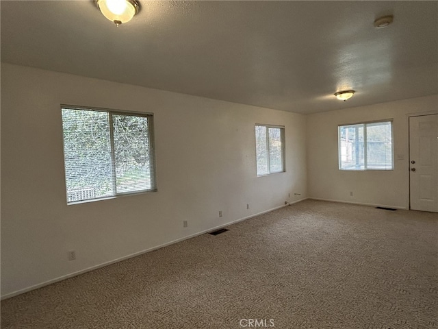 spare room featuring light colored carpet, baseboards, and visible vents