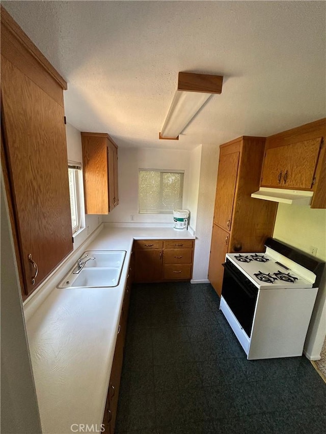 kitchen featuring brown cabinetry, white range with gas stovetop, and a sink