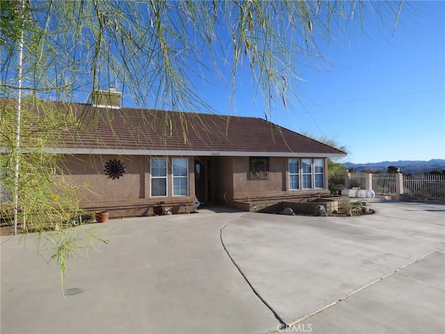 48628 Adeline Way, Morongo Valley, CA 92256 - view of front of house with a shingled roof, stucco siding, a chimney, and fence