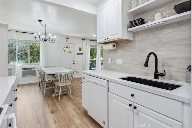 kitchen with tasteful backsplash, a sink, dishwasher, white cabinetry, and light wood-type flooring