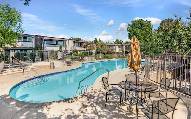 community pool with a patio and fence