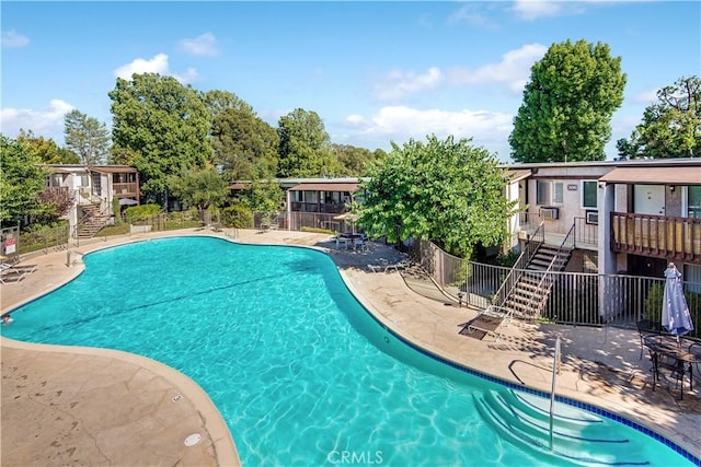 pool with fence, a patio area, and stairway