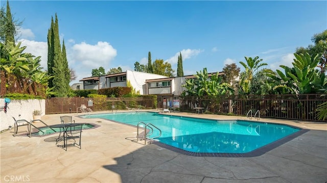 community pool with fence and a patio area