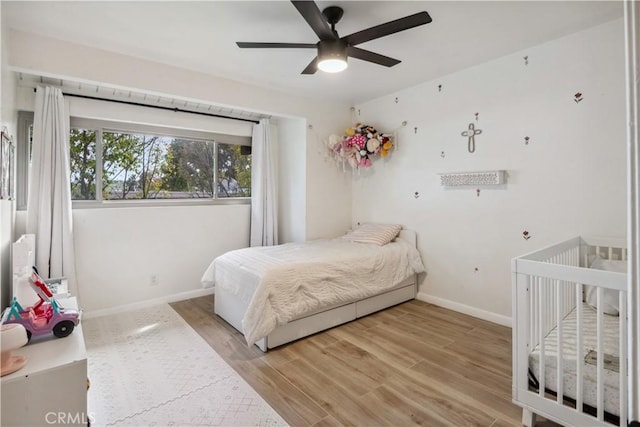 bedroom with a ceiling fan, baseboards, and wood finished floors