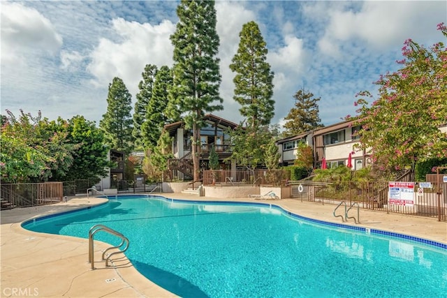 community pool with a patio and fence