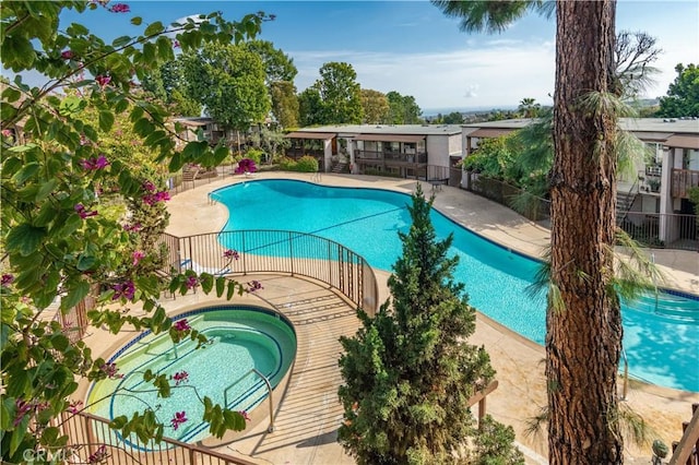 pool with a community hot tub, a patio area, and fence