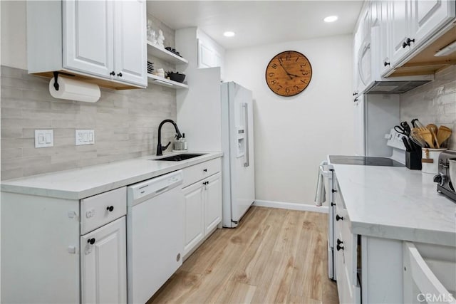kitchen with white appliances, white cabinetry, a sink, light wood finished floors, and backsplash
