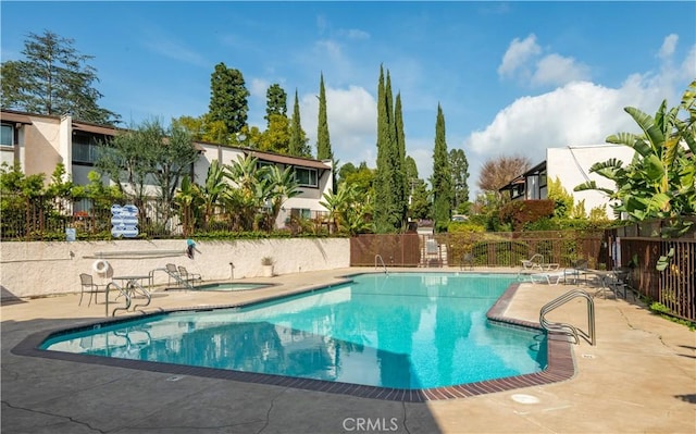 pool featuring a patio, a community hot tub, and fence