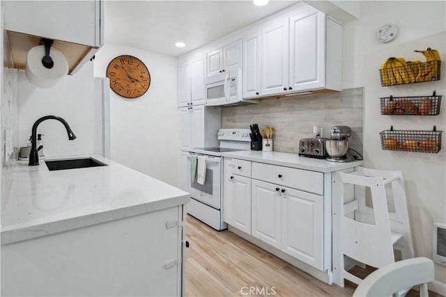 kitchen with a sink, white cabinets, white appliances, and tasteful backsplash
