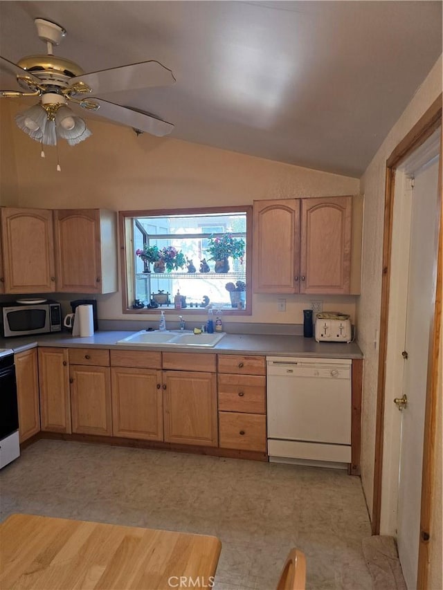 kitchen with lofted ceiling, light brown cabinetry, white dishwasher, stainless steel microwave, and a sink