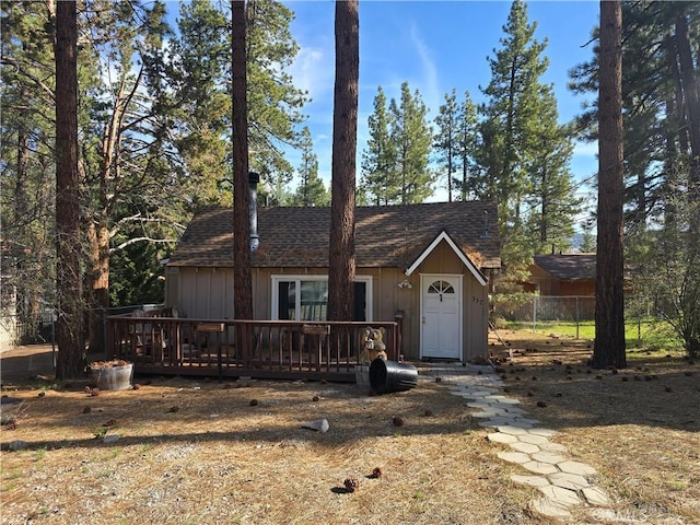 view of front of home with fence, a wooden deck, and a shingled roof