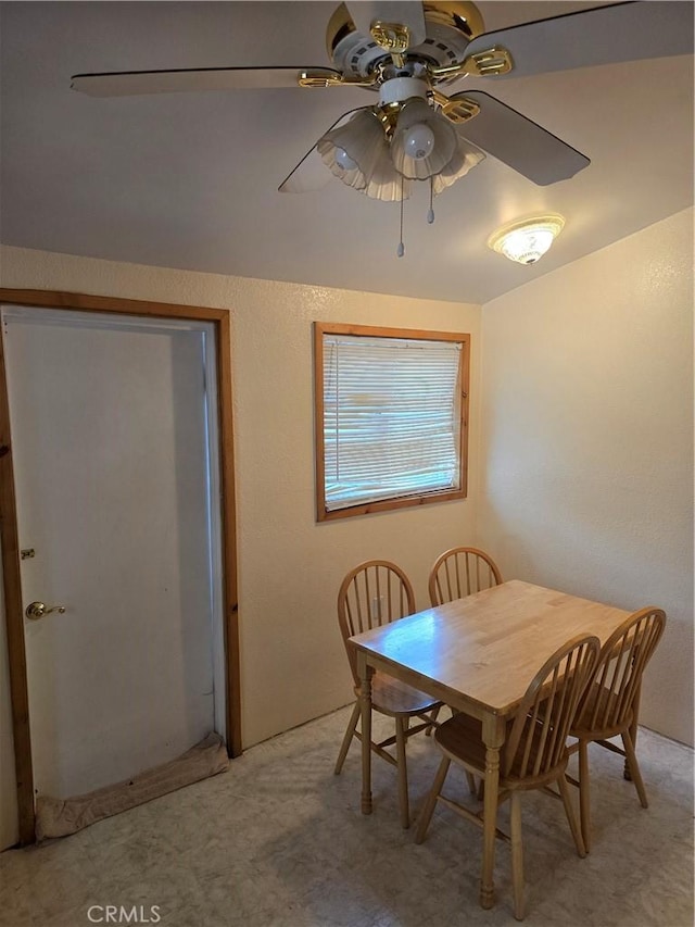 dining area with ceiling fan and light colored carpet