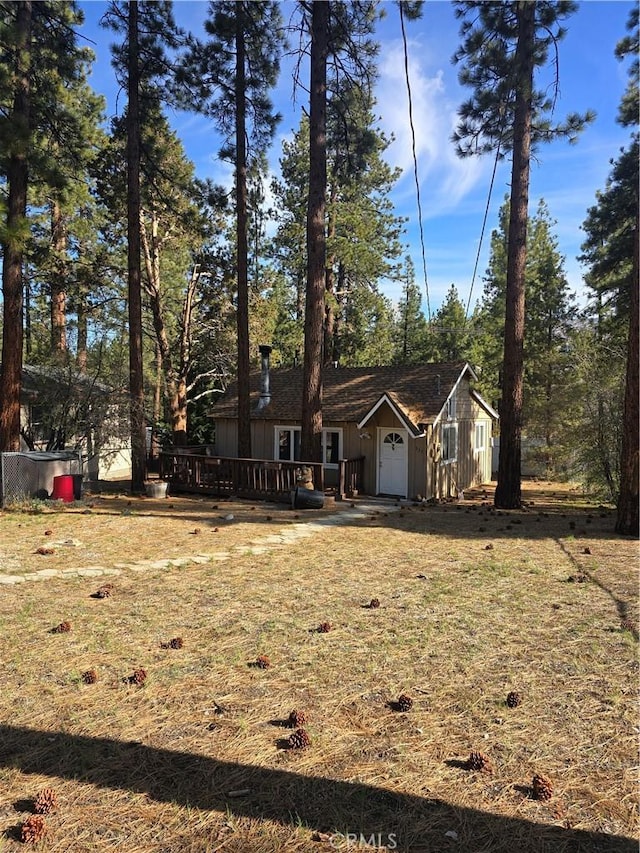 view of front of property with board and batten siding, a wooden deck, and a front yard