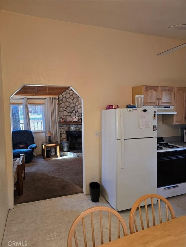 kitchen featuring range with gas stovetop, freestanding refrigerator, a fireplace, open floor plan, and light colored carpet