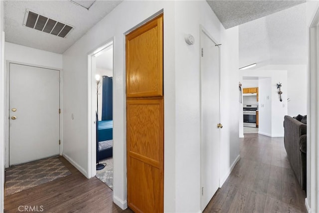 hall with baseboards, dark wood finished floors, a textured ceiling, and visible vents
