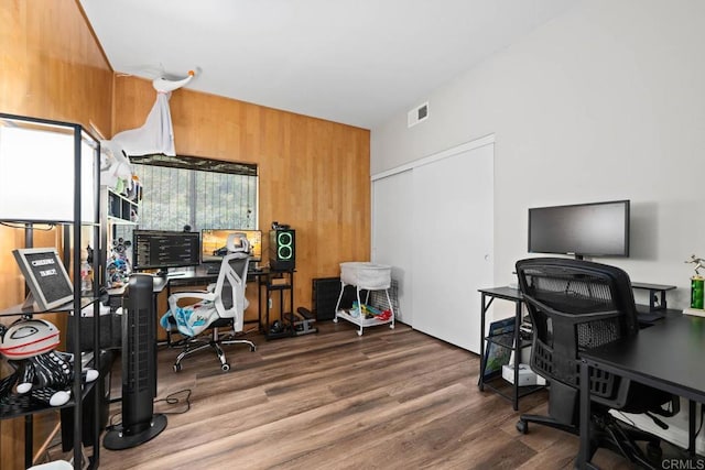 office area featuring wood walls, visible vents, and wood finished floors