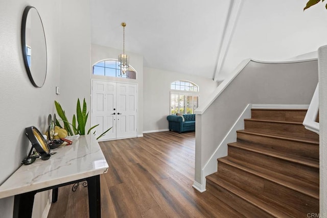 foyer entrance with dark wood-type flooring, baseboards, lofted ceiling, and stairway