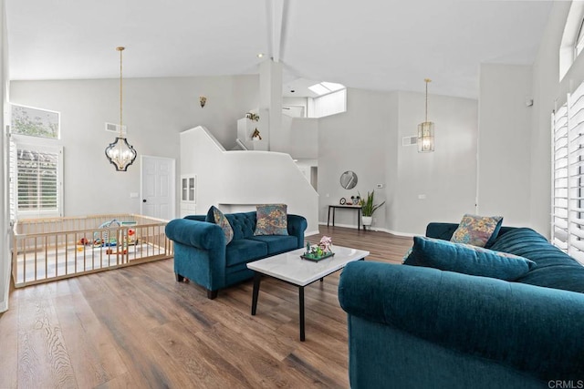 living area featuring visible vents, wood finished floors, high vaulted ceiling, baseboards, and a chandelier