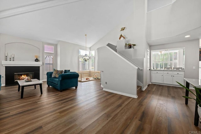 living room featuring a notable chandelier, a wealth of natural light, high vaulted ceiling, and stairway