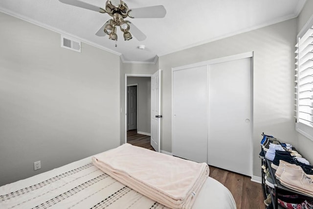bedroom featuring ornamental molding, a closet, dark wood-style flooring, and visible vents
