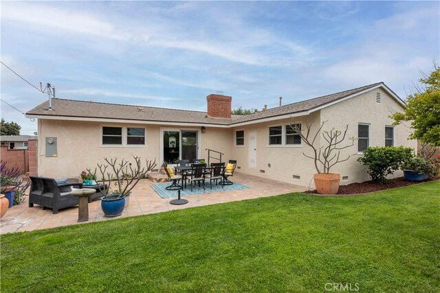 rear view of property featuring crawl space, stucco siding, a yard, and a patio area