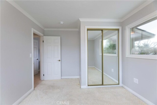 unfurnished bedroom featuring carpet floors, crown molding, a closet, and baseboards