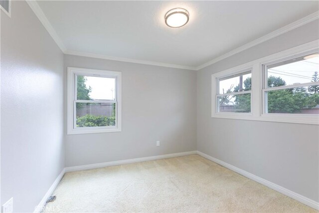 unfurnished room featuring light colored carpet, plenty of natural light, crown molding, and baseboards