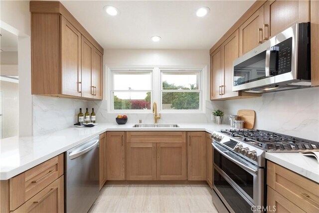 kitchen with appliances with stainless steel finishes, a sink, recessed lighting, decorative backsplash, and light countertops