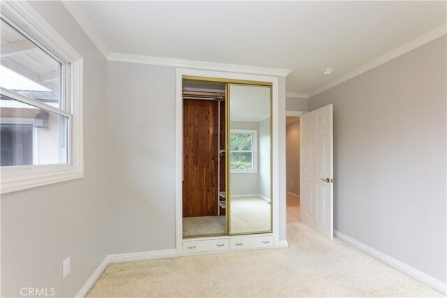 unfurnished bedroom with carpet flooring, ornamental molding, baseboards, and a closet