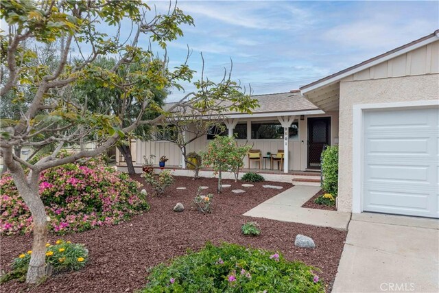 property entrance featuring stucco siding, covered porch, and board and batten siding