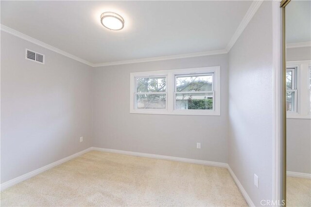 unfurnished room with light colored carpet, crown molding, and baseboards