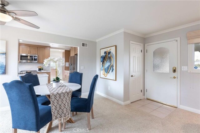 dining room with light carpet, a ceiling fan, baseboards, and ornamental molding