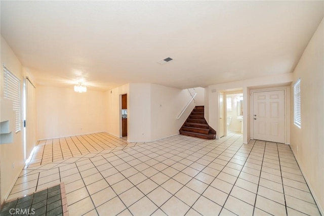 unfurnished living room featuring light tile patterned floors, stairway, and plenty of natural light