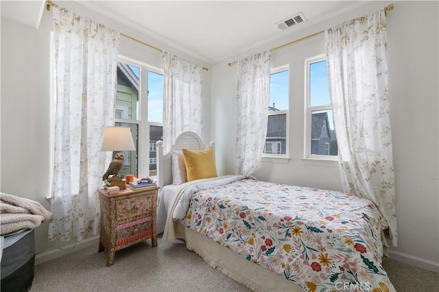 carpeted bedroom featuring baseboards, visible vents, and multiple windows