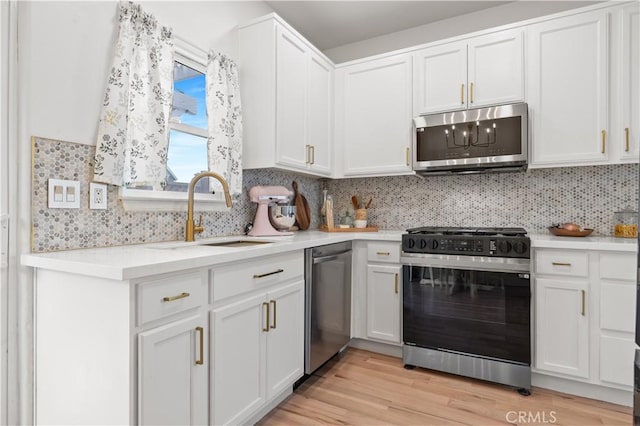 kitchen with a sink, light countertops, stainless steel appliances, and white cabinetry