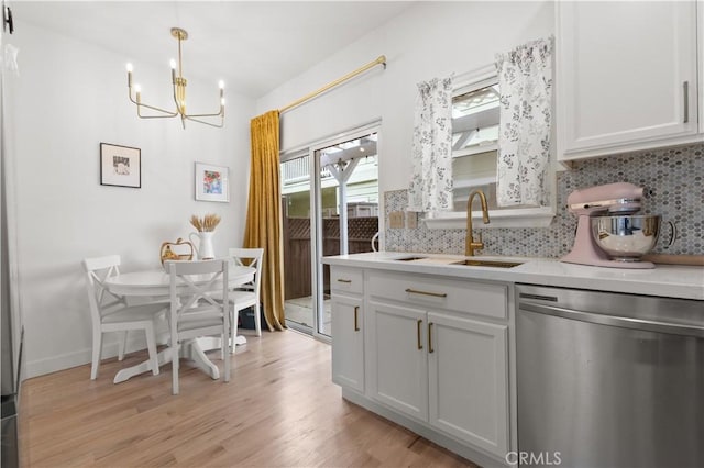 kitchen featuring stainless steel dishwasher, a sink, a notable chandelier, and tasteful backsplash