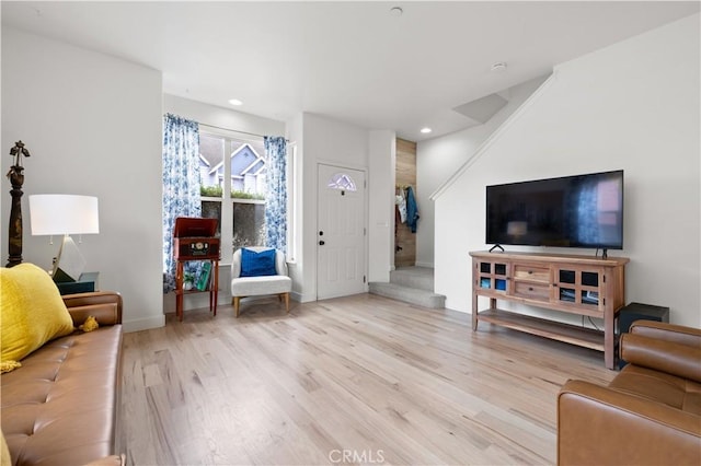 living area with recessed lighting, baseboards, stairs, and wood finished floors