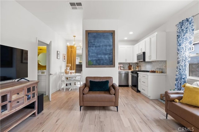 living area with recessed lighting, baseboards, light wood-type flooring, and visible vents