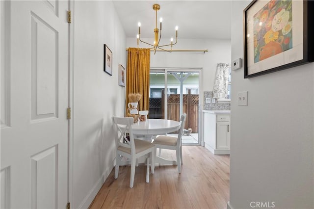 dining space featuring baseboards, light wood finished floors, and a notable chandelier