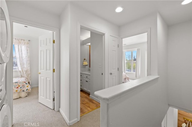 corridor featuring baseboards, recessed lighting, and light colored carpet