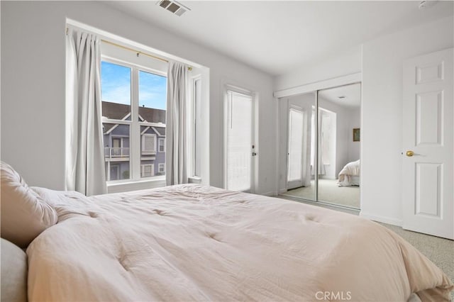 bedroom with visible vents, baseboards, carpet floors, and a closet