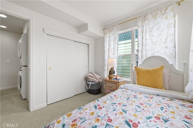 bedroom with carpet floors, stacked washing maching and dryer, and a closet