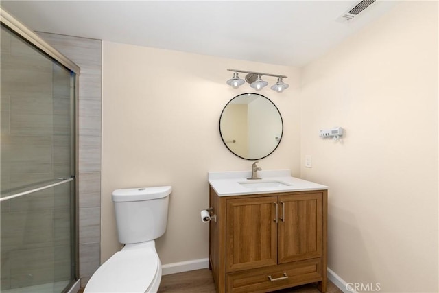 full bathroom featuring toilet, baseboards, vanity, and tiled shower