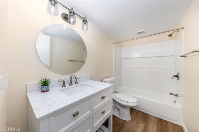 full bathroom featuring toilet, visible vents, vanity, wood finished floors, and washtub / shower combination