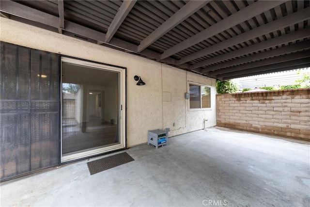 view of exterior entry with stucco siding and a patio