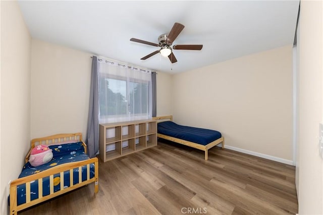 bedroom featuring wood finished floors, baseboards, and a ceiling fan